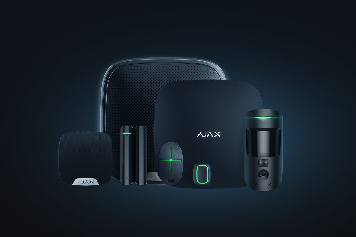 Kit d’alarme noir sur fond sombre : centrale, sirène, détecteurs et télécommande.